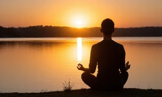 Person meditating calmly by a serene lake at sunrise, indicating peace and improved mood. No text.